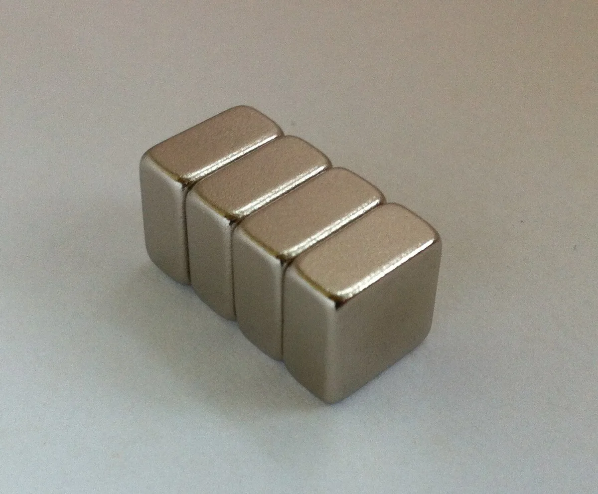 Enkele ronde neodymium magneetschijfjes met een metaalglans, los naast elkaar op een lichte ondergrond.